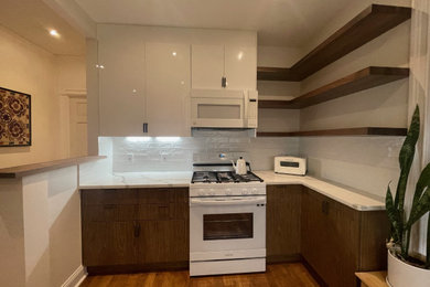 ニューヨークにある高級な小さなコンテンポラリースタイルのおしゃれなキッチン (シングルシンク、フラットパネル扉のキャビネット、珪岩カウンター、白いキッチンパネル、セラミックタイルのキッチンパネル、白い調理設備、合板フローリング、茶色い床、白いキッチンカウンター) の写真