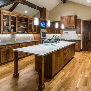 Cette image montre une grande arrière-cuisine asiatique en U avec un évier encastré, un placard à porte affleurante, des portes de placard en bois sombre, une crédence grise, un électroménager en acier inoxydable, un sol en bois clair et un îlot central.