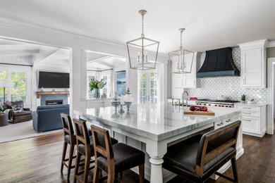 Mid-sized transitional kitchen in DC Metro with a drop-in sink, flat-panel cabinets, white cabinets, marble benchtops, white splashback, marble splashback, stainless steel appliances, dark hardwood floors, multiple islands, brown floor and white benchtop.