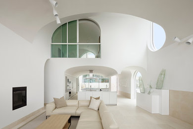 This is an example of a modern open concept living room in Los Angeles with white walls and a plaster fireplace surround.
