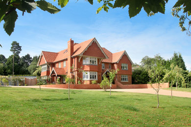 Photo of a red contemporary two floor house exterior in Surrey with mixed cladding and a pitched roof.