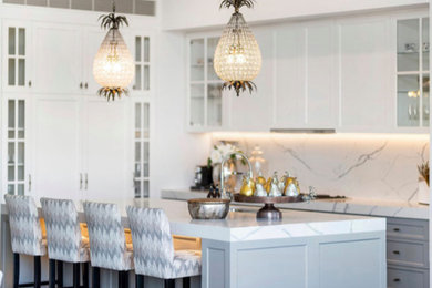 This is an example of a mid-sized galley eat-in kitchen in Melbourne with an undermount sink, glass-front cabinets, white cabinets, marble benchtops, white splashback, marble splashback, stainless steel appliances, with island and white benchtop.