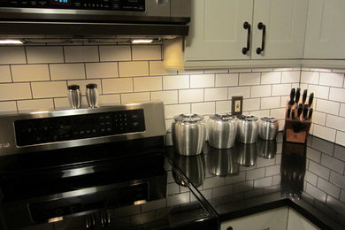 Enclosed kitchen - mid-sized craftsman l-shaped medium tone wood floor and brown floor enclosed kitchen idea in Columbus with an undermount sink, shaker cabinets, white cabinets, quartz countertops, white backsplash, subway tile backsplash, white appliances and no island