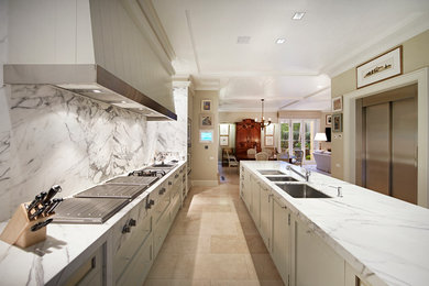 Expansive contemporary galley eat-in kitchen in Melbourne with a triple-bowl sink, recessed-panel cabinets, grey cabinets, marble benchtops, white splashback, stone slab splashback, stainless steel appliances, travertine floors and with island.