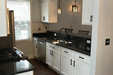 Inspiration for a transitional galley medium tone wood floor and brown floor eat-in kitchen remodel in Other with an undermount sink, shaker cabinets, white cabinets, granite countertops, gray backsplash, ceramic backsplash and stainless steel appliances