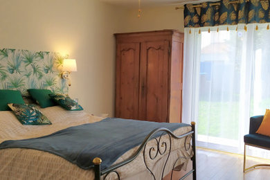 Modelo de dormitorio principal clásico renovado de tamaño medio con paredes blancas, suelo de madera clara y papel pintado