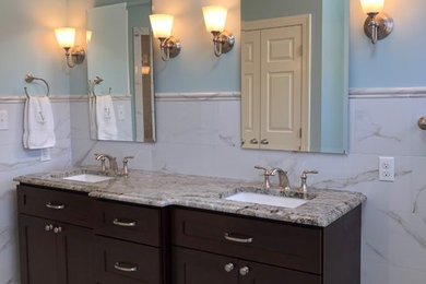 Example of a large transitional master porcelain tile porcelain tile and white floor corner shower design in Raleigh with shaker cabinets, dark wood cabinets, blue walls, an undermount sink, granite countertops and a hinged shower door
