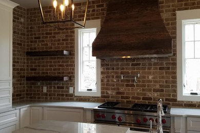 Inspiration for a rustic u-shaped dark wood floor kitchen remodel in Atlanta with a farmhouse sink, shaker cabinets, white cabinets, brick backsplash, stainless steel appliances and an island