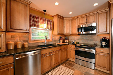 Inspiration for a mid-sized timeless l-shaped travertine floor kitchen remodel in Boston with an undermount sink, raised-panel cabinets, granite countertops, multicolored backsplash, subway tile backsplash and stainless steel appliances