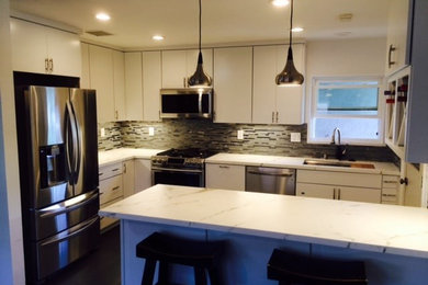Mid-sized transitional u-shaped separate kitchen in San Diego with an undermount sink, flat-panel cabinets, white cabinets, quartzite benchtops, multi-coloured splashback, glass tile splashback, white appliances and a peninsula.