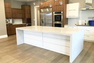 Design ideas for a modern kitchen in Toronto with flat-panel cabinets, white cabinets, quartz benchtops, white splashback, glass tile splashback and stainless steel appliances.