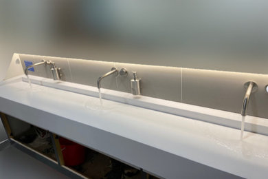 This is an example of a medium sized contemporary cloakroom in Essex with solid surface worktops, white worktops and a floating vanity unit.