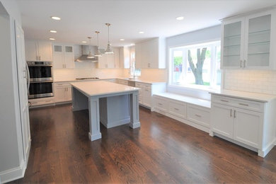 Inspiration for a large transitional u-shaped dark wood floor and brown floor open concept kitchen remodel in Chicago with an undermount sink, shaker cabinets, white cabinets, quartz countertops, white backsplash, subway tile backsplash, stainless steel appliances and an island