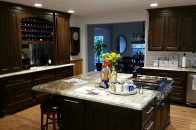 Example of a mid-sized classic u-shaped medium tone wood floor and brown floor open concept kitchen design in Portland with an undermount sink, shaker cabinets, dark wood cabinets, granite countertops, stainless steel appliances and an island