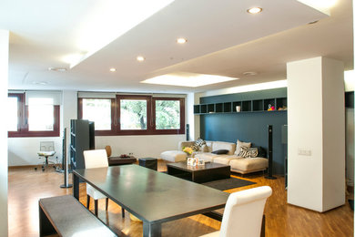 Diseño de sala de estar tipo loft moderna grande con paredes negras, suelo de madera en tonos medios y televisor independiente