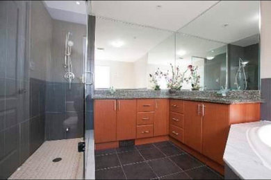 Идея дизайна: большая главная ванная комната в классическом стиле с плоскими фасадами, светлыми деревянными фасадами, угловой ванной, двойным душем, унитазом-моноблоком, серой плиткой, керамогранитной плиткой, серыми стенами, врезной раковиной, столешницей из гранита, душем с распашными дверями и серой столешницей