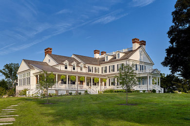Country three-storey white house exterior in Philadelphia with wood siding, a gable roof and a mixed roof.
