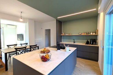 Foto di un'ampia cucina minimal con lavello integrato, ante grigie, top in superficie solida, paraspruzzi verde, elettrodomestici neri, pavimento in gres porcellanato, pavimento beige, top beige e soffitto ribassato