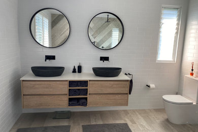 Photo of a large contemporary bathroom in Sydney with a one-piece toilet, white tile, subway tile, cement tiles, a vessel sink, engineered quartz benchtops, grey floor, a double vanity and a floating vanity.