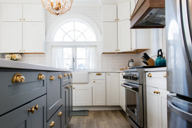 ニューヨークにある高級な広いシャビーシック調のおしゃれなキッチン (エプロンフロントシンク、シェーカースタイル扉のキャビネット、青いキャビネット、クオーツストーンカウンター、白いキッチンパネル、サブウェイタイルのキッチンパネル、シルバーの調理設備、淡色無垢フローリング、茶色い床、白いキッチンカウンター) の写真
