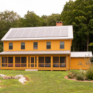 ニューヨークのカントリー風おしゃれな二階建ての家 (切妻屋根、オレンジの外壁) の写真