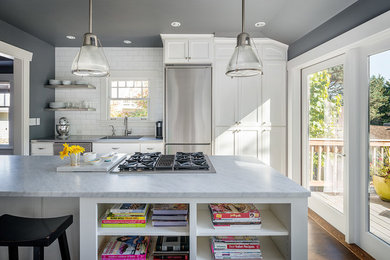 Inspiration for a large transitional kitchen in Seattle with an undermount sink, shaker cabinets, white cabinets, marble benchtops, white splashback, subway tile splashback, stainless steel appliances, medium hardwood floors, with island and brown floor.