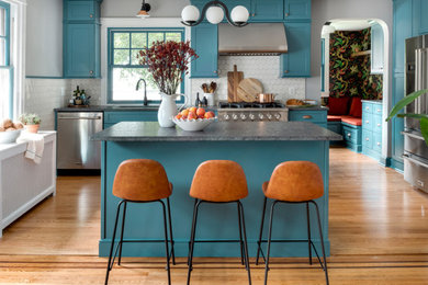 Eat-in kitchen - mid-sized eclectic single-wall light wood floor and orange floor eat-in kitchen idea in Philadelphia with an undermount sink, shaker cabinets, blue cabinets, granite countertops, white backsplash, ceramic backsplash, stainless steel appliances, an island and gray countertops
