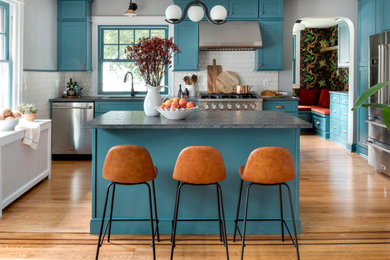 Eat-in kitchen - mid-sized eclectic single-wall light wood floor and orange floor eat-in kitchen idea in Philadelphia with an undermount sink, shaker cabinets, blue cabinets, granite countertops, white backsplash, ceramic backsplash, stainless steel appliances, an island and gray countertops