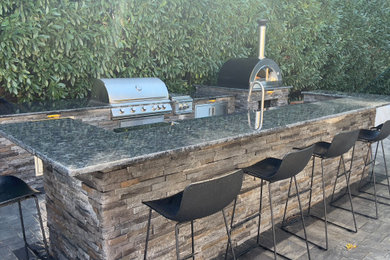 Example of a large tuscan backyard concrete paver patio kitchen design in New York