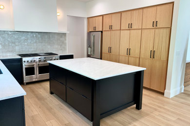 Example of a large danish u-shaped vinyl floor and brown floor eat-in kitchen design in Other with an undermount sink, shaker cabinets, black cabinets, marble countertops, multicolored backsplash, stainless steel appliances, an island and white countertops