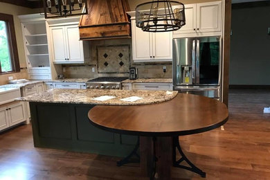Inspiration for a mid-sized craftsman l-shaped medium tone wood floor and brown floor kitchen remodel in New York with a farmhouse sink, beaded inset cabinets, white cabinets, granite countertops, gray backsplash, stone tile backsplash, stainless steel appliances, an island and gray countertops