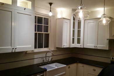 Example of a small transitional u-shaped enclosed kitchen design in Boise with a farmhouse sink, shaker cabinets, white cabinets, white backsplash, subway tile backsplash, stainless steel appliances, a peninsula and soapstone countertops