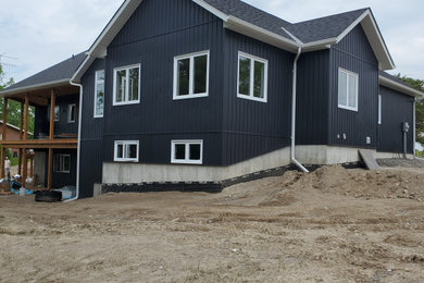 Example of a large country blue one-story vinyl and board and batten house exterior design in Toronto with a hip roof, a shingle roof and a black roof