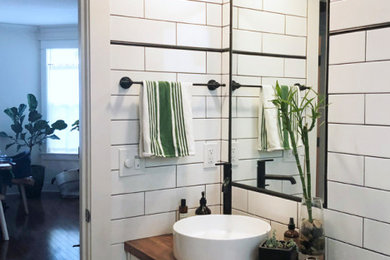 Small urban white tile and subway tile porcelain tile, black floor and single-sink bathroom photo in Portland with shaker cabinets, white cabinets, white walls, a vessel sink, wood countertops, brown countertops and a floating vanity