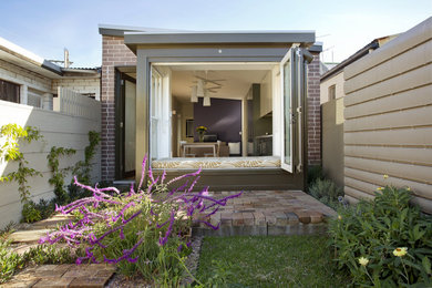 Small tropical one-storey brick multi-coloured exterior in Sydney with a shed roof, a metal roof and a grey roof.