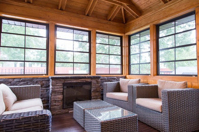 Example of a mid-sized minimalist dark wood floor and brown floor sunroom design in Other with a standard fireplace, a stone fireplace and a standard ceiling