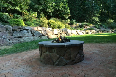 Photo of a mid-sized traditional full sun backyard brick landscaping in Other with a fire pit.