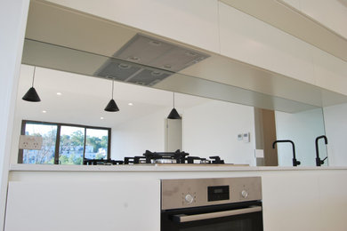 Modern kitchen in Other with mirror splashback.