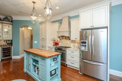 Enclosed kitchen - large cottage u-shaped light wood floor enclosed kitchen idea in Atlanta with recessed-panel cabinets, white cabinets, granite countertops, beige backsplash, matchstick tile backsplash, stainless steel appliances and an island