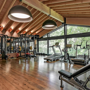 トロントの巨大なおしゃれなトレーニングルーム (赤い壁、濃色無垢フローリング、茶色い床) の写真