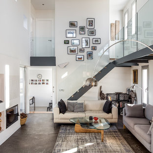 Modelo de salón abierto, contemporáneo, con paredes blancas, suelo gris, chimenea tradicional y televisor colgado en la pared