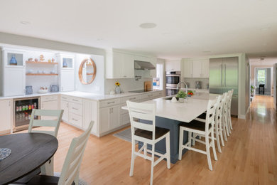 Inspiration for a huge transitional l-shaped light wood floor and beige floor kitchen pantry remodel in Boston with an undermount sink, shaker cabinets, white cabinets, quartz countertops, white backsplash, subway tile backsplash, stainless steel appliances, an island and white countertops