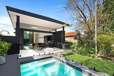 Diseño de piscina elevada minimalista de tamaño medio rectangular en patio trasero con paisajismo de piscina y entablado