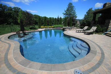 Design ideas for a large contemporary backyard custom-shaped pool in Philadelphia with a hot tub and concrete pavers.