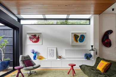 Photo of a mid-sized contemporary open concept living room in Melbourne with white walls, carpet, no tv, green floor and timber.