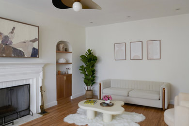 Example of a transitional medium tone wood floor living room design in New York with a standard fireplace and a wood fireplace surround