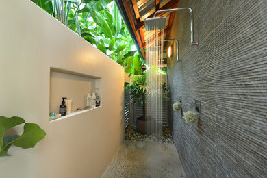 Photo of a small tropical backyard patio in Cairns with an outdoor shower, concrete slab and a roof extension.