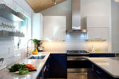 Mid-sized trendy u-shaped light wood floor and brown floor eat-in kitchen photo in Portland Maine with an island, flat-panel cabinets, white backsplash, stainless steel appliances, an undermount sink, blue cabinets, ceramic backsplash and gray countertops