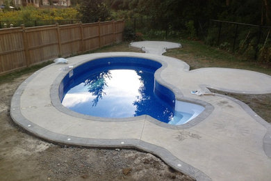 Example of a small classic backyard stamped concrete and kidney-shaped pool design in Toronto