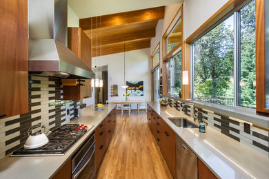 Inspiration for a large contemporary galley eat-in kitchen in Portland with flat-panel cabinets, grey splashback, ceramic splashback, no island, an undermount sink, medium wood cabinets, medium hardwood floors, stainless steel appliances, solid surface benchtops and beige floor.